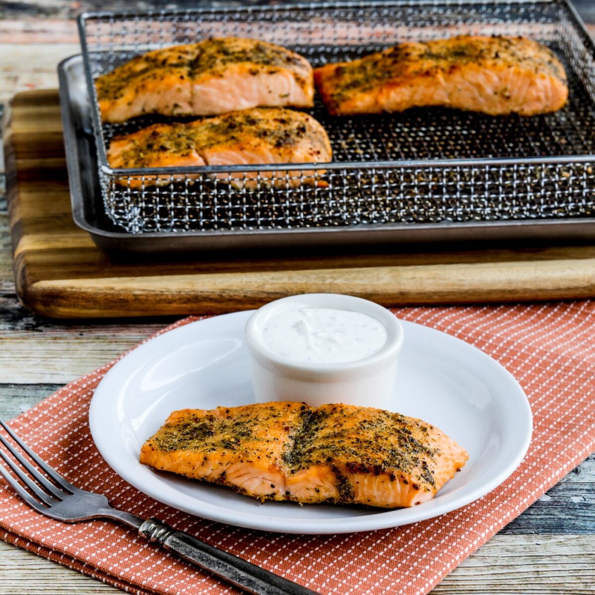 Greek Salmon with Tzatziki Sauce shown on plate in front of air fryer rack.