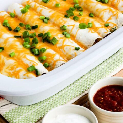 Egg Burritos for a Crowd shown in casserole crock pot with salsa and sour cream in bowls.