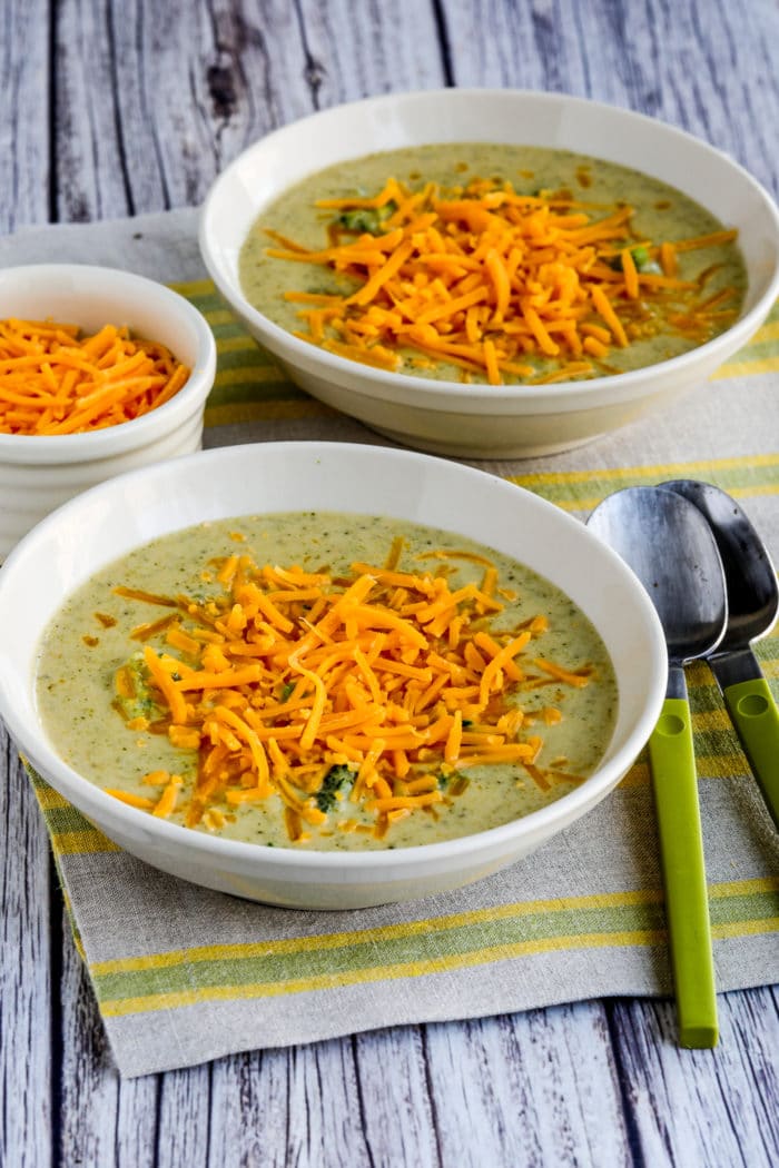 Cheesy Broccoli and Cauliflower Soup in two soup bowls with cheese added