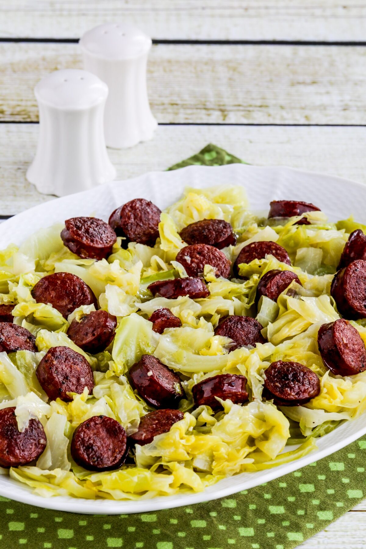 Instant Pot Cabbage and Sausage on serving platter with salt-pepper in background