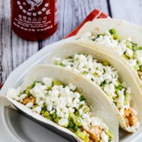 Instant Pot Sriracha Chicken Tacos finished tacos with Queso Fresca and Sriracha bottle in back