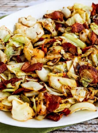 Square image of Fried Cabbage with Bacon shown on serving plate.