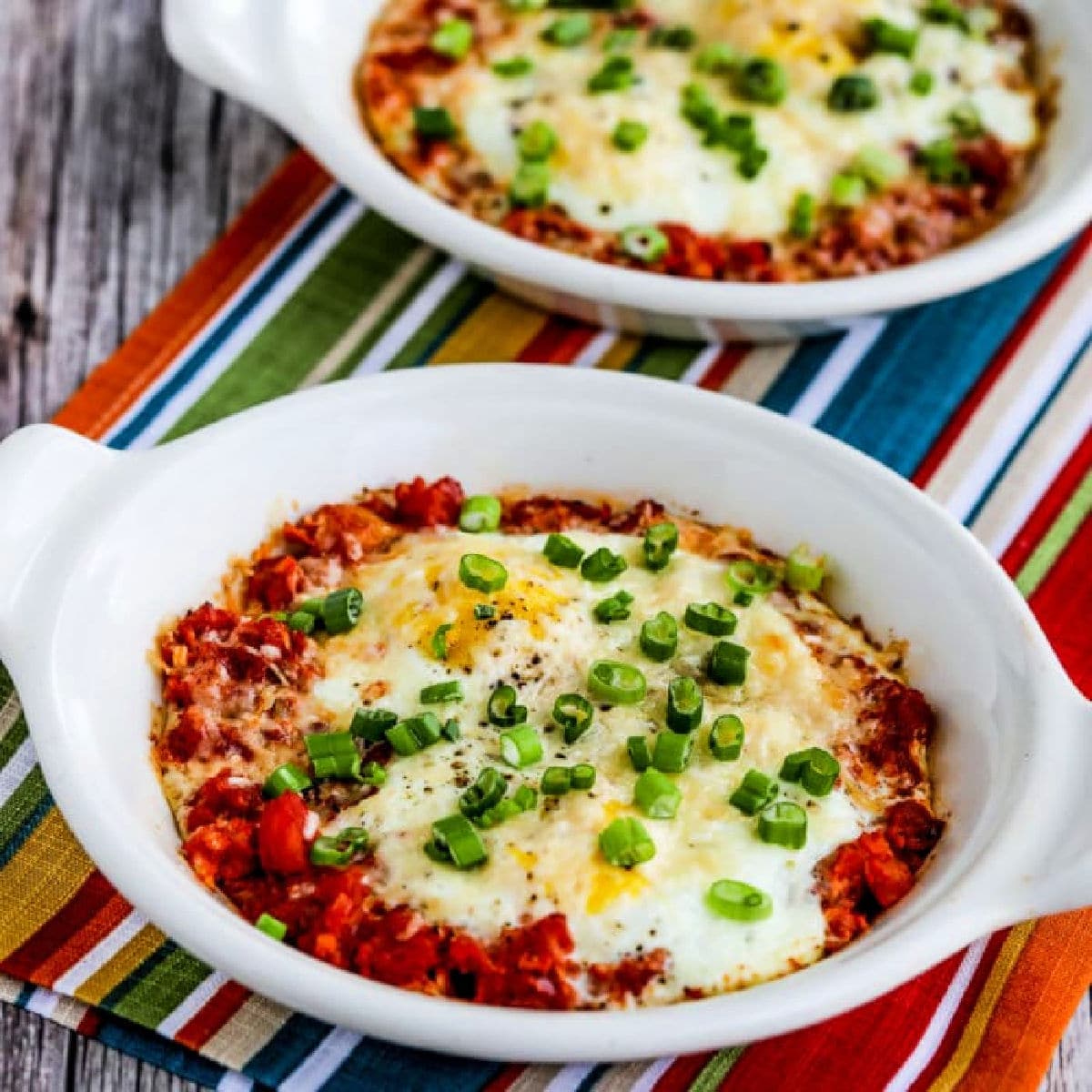 Square image for Tuscan Baked Eggs with Tomatoes shown in two gratin dishes.