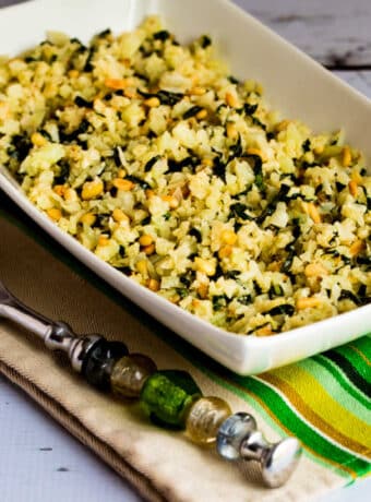 Square image of Cauliflower Rice with Basil, Parmesan, and Pine Nuts in serving bowl on napkin.