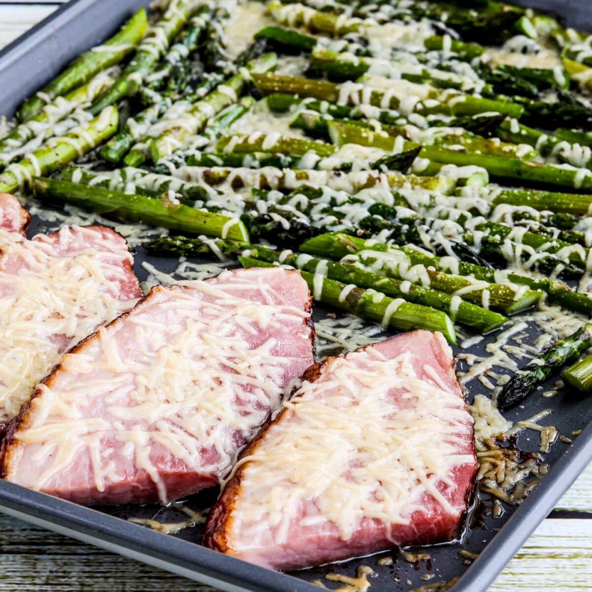 Baked Ham and Asparagus shown on sheet pan with Parmesan cheese sprinkled over.