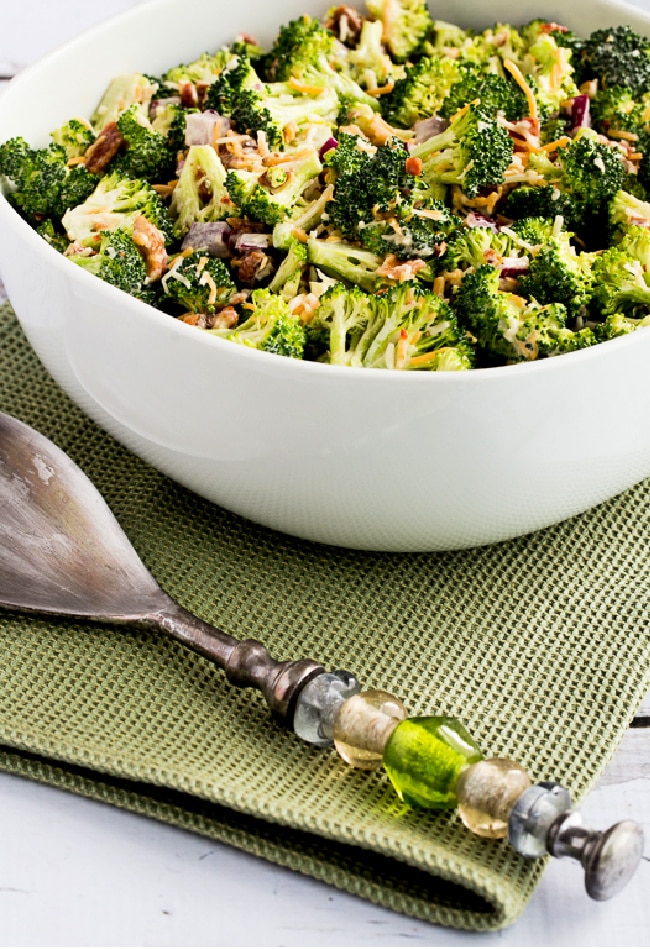 Sweet and Sour Broccoli Salad in serving bowl with serving spoon and napkin