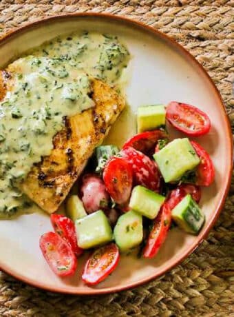 Grilled Halibut with Basil Vinaigrette on serving plate with tomato-cucumber-salad