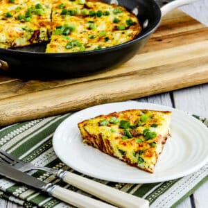 Square image of Bacon Frittata with Two Cheeses shown with one slice on plate and frittata in back.