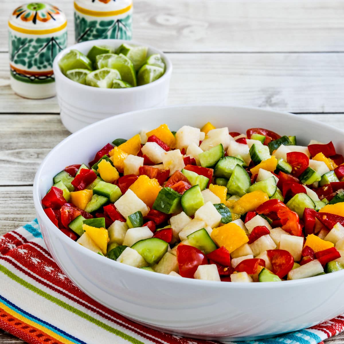 Laurel's Jicama Salad shown in serving bowl with limes and Mexican salt-pepper in back.