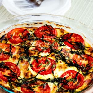 Crustless Three-Cheese Tomato-Basil Quiche shown in baking dish with plates-forks in background