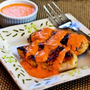 Square image of Grilled Garlic Chicken with Red Pepper Aioli Sauce close-up shot of chicken on plate drizzled with sauce.