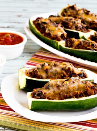 square image of Taco Zucchini Boats on serving plate and platter with salsa on the side
