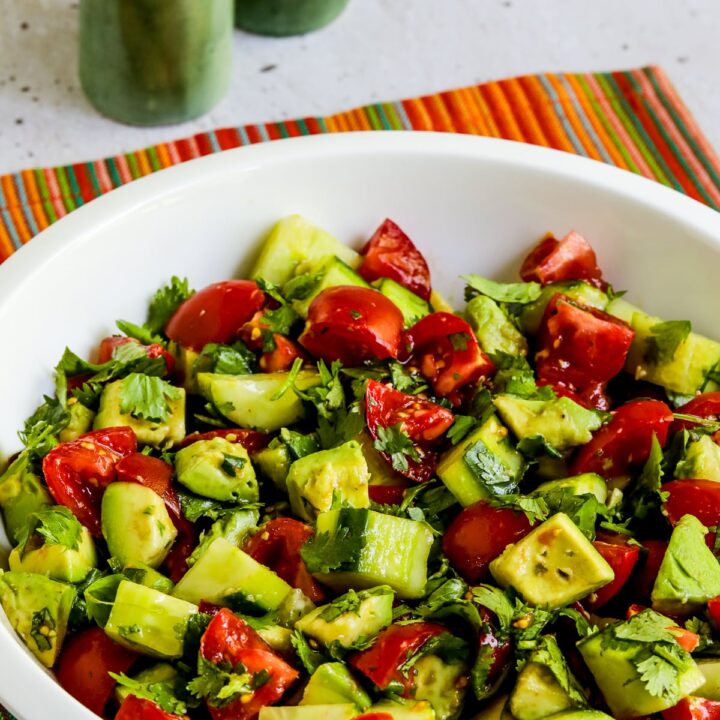 Tomato Salad with Cucumbers, Avocado, and Cilantro shown in serving bowl with striped napkin.