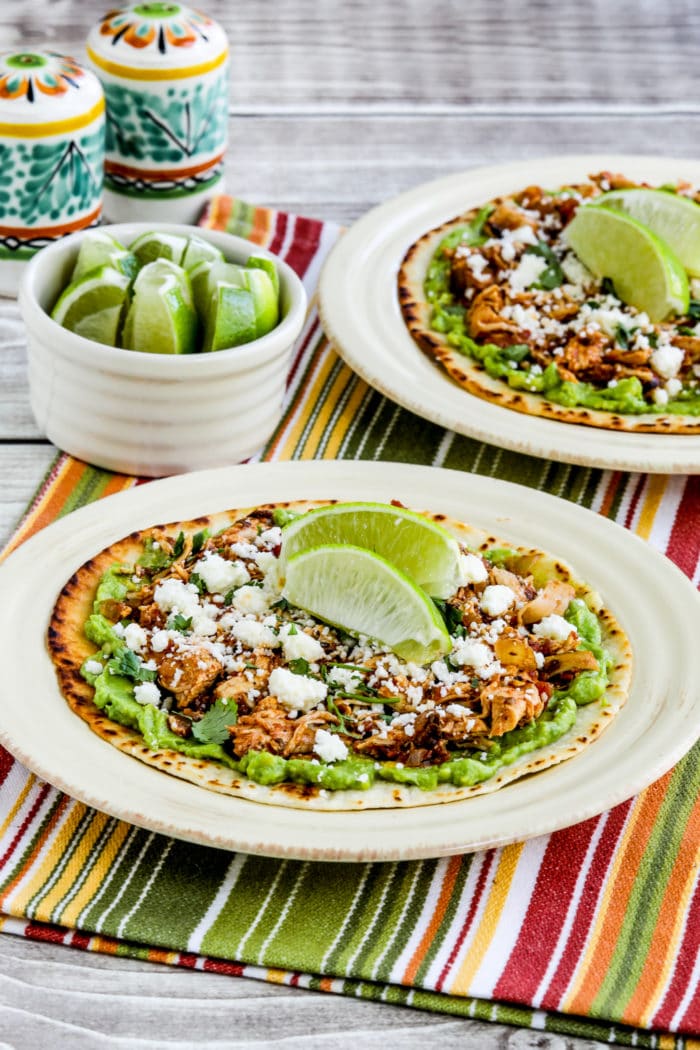 Instant Pot chicken tinga on tostada with guacamole and lime background