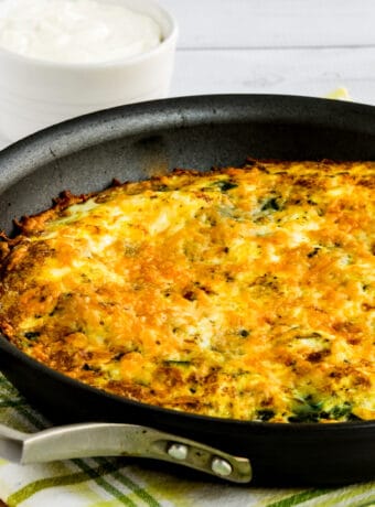 square image of zucchini frittata in pan on cutting board