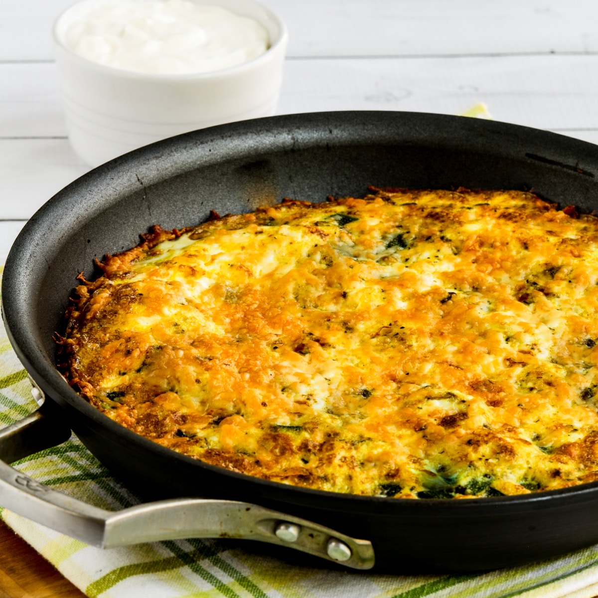 square image of zucchini frittata in pan on cutting board