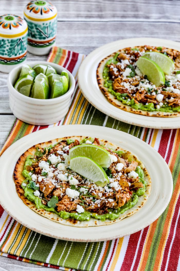 Close up photo of instant pot chicken tinga on tostada with guacamole and lime