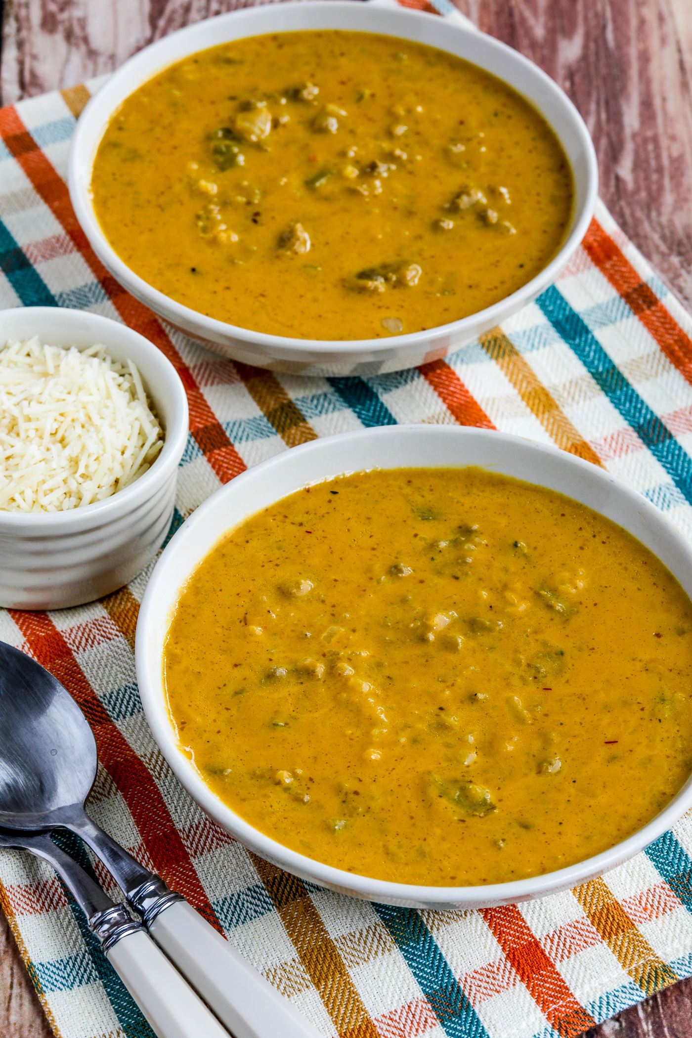 Instant Pot Pumpkin Soup in two serving bowls with spoons and Parmesan cheese