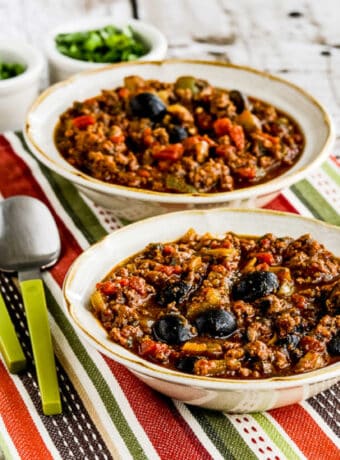 Pumpkin Chili with Beef, Peppers, and Olives in two serving. bowls, square image