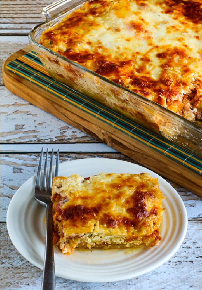 One serving of mock lasagna spaghetti squash casserole on a plate and a casserole dish in the background