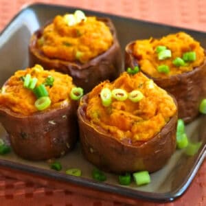 square image of twice-baked sweet potatoes on serving plate with green onion garnish