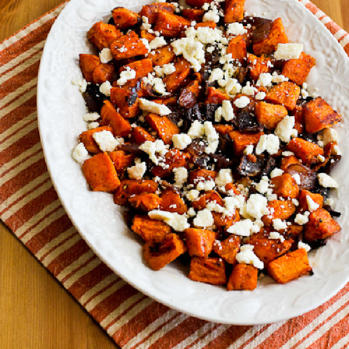 Roasted Sweet Potatoes with Feta shown on serving platter with striped napkin