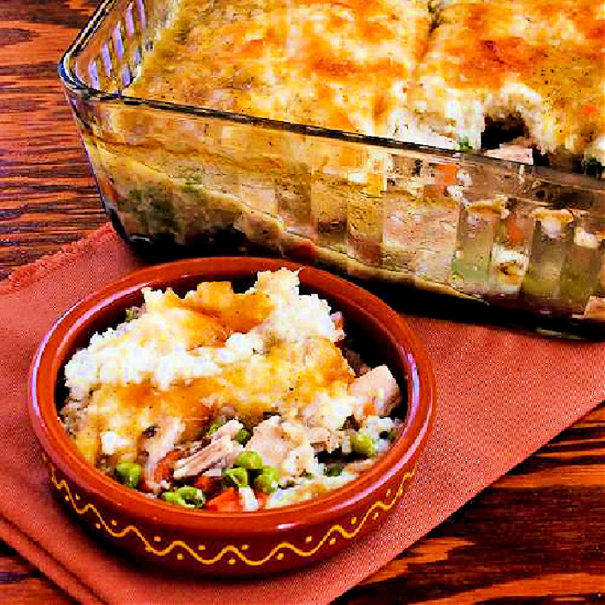 Square image for Turkey Shepherd's Pie with Cauliflower with one serving in bowl and baking dish in back.