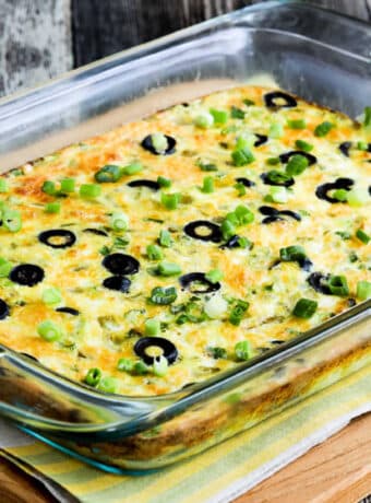 Square image of Bobbi's Egg Casserole with Green Chiles and Cheese shown in baking dish on napkin.