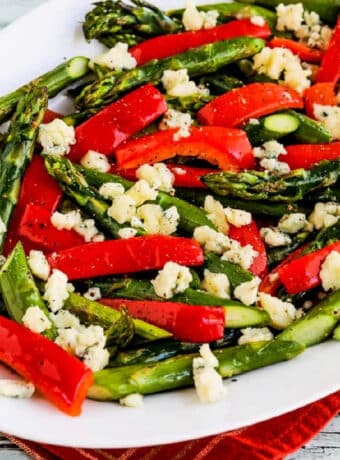 Square image of Roasted Asparagus and Peppers shown on serving platter, with crumbled Gorgonzola.