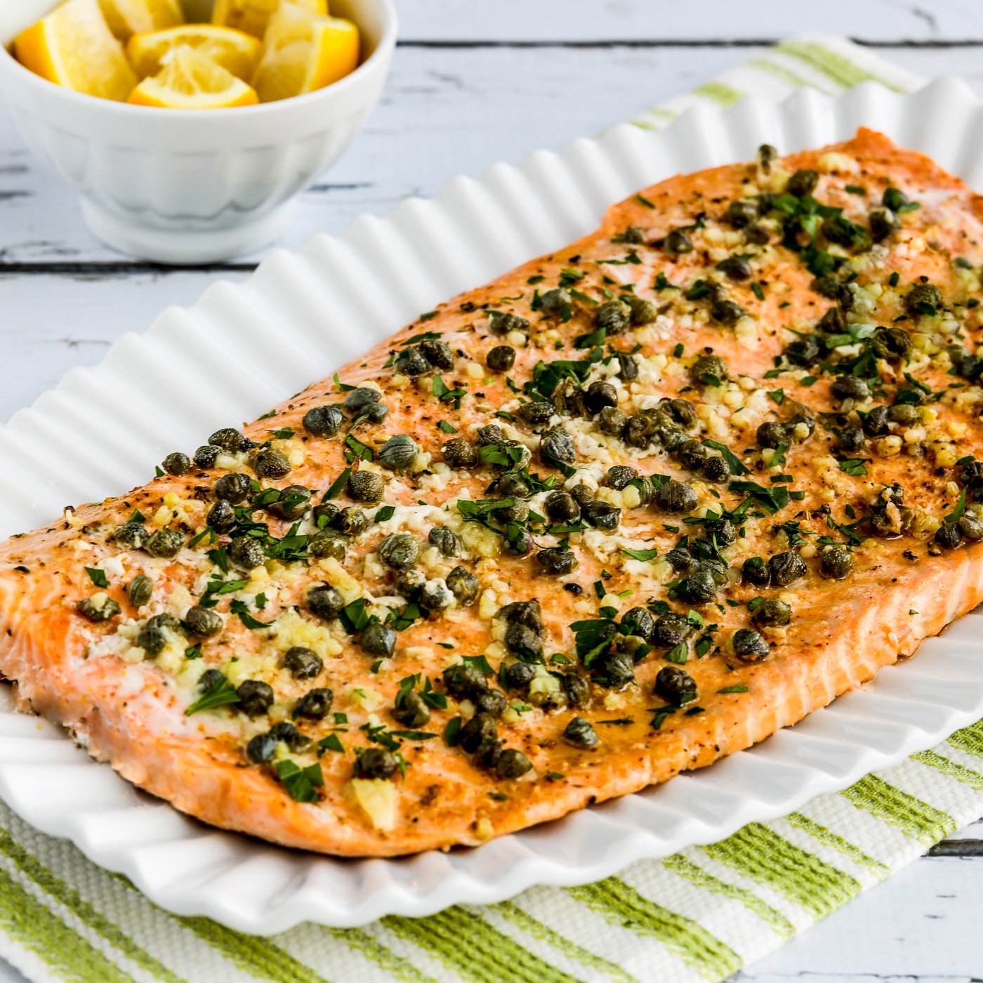 Slow Cooked Salmon square image showing salmon on serving plate with lemons in background