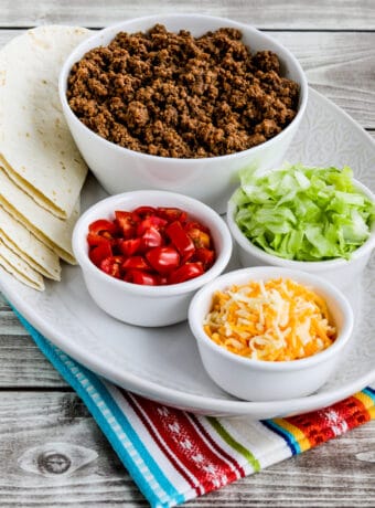 Instant Pot Taco Meat shown with lettuce, tomatoes, cheese, and tortillas