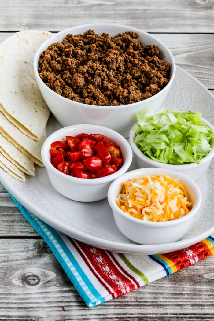 Instant Pot Taco Meat shown with lettuce, tomatoes, cheese, and tortillas