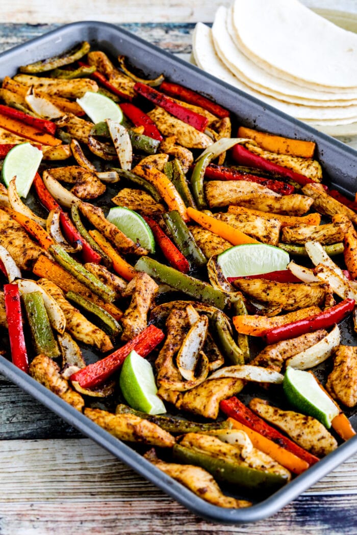 Chicken Fajitas shown on sheet pan with tortillas and limes