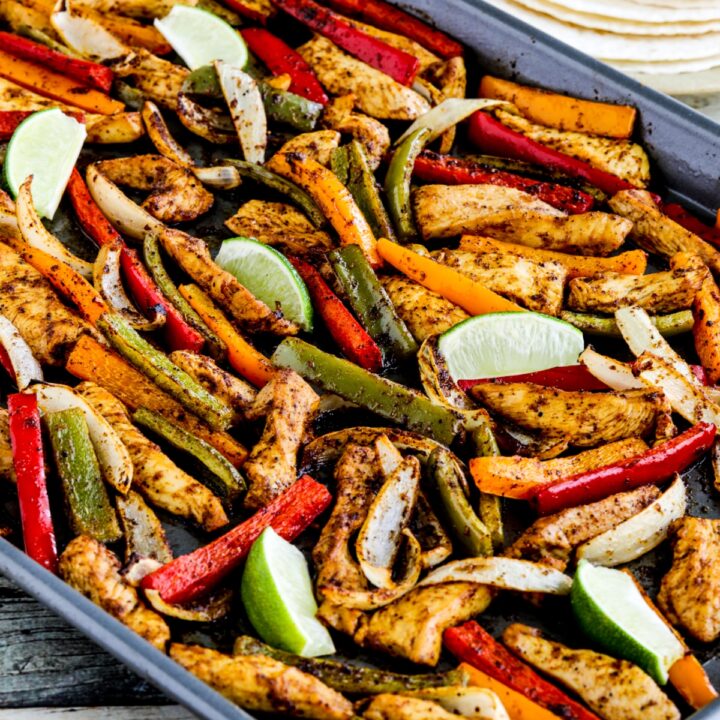 Chicken Fajitas shown on sheet pan with tortillas and limes