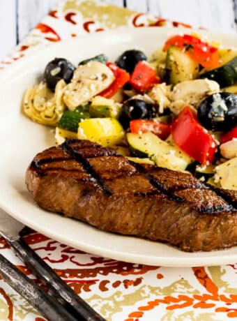 Easy Steak Marinade Photo showing grilled steak on plate with zucchini-artichoke salad.