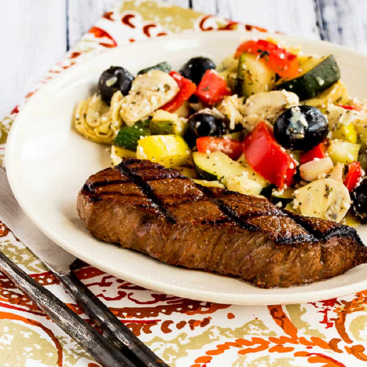 Easy Steak Marinade Photo showing grilled steak on plate with zucchini-artichoke salad.