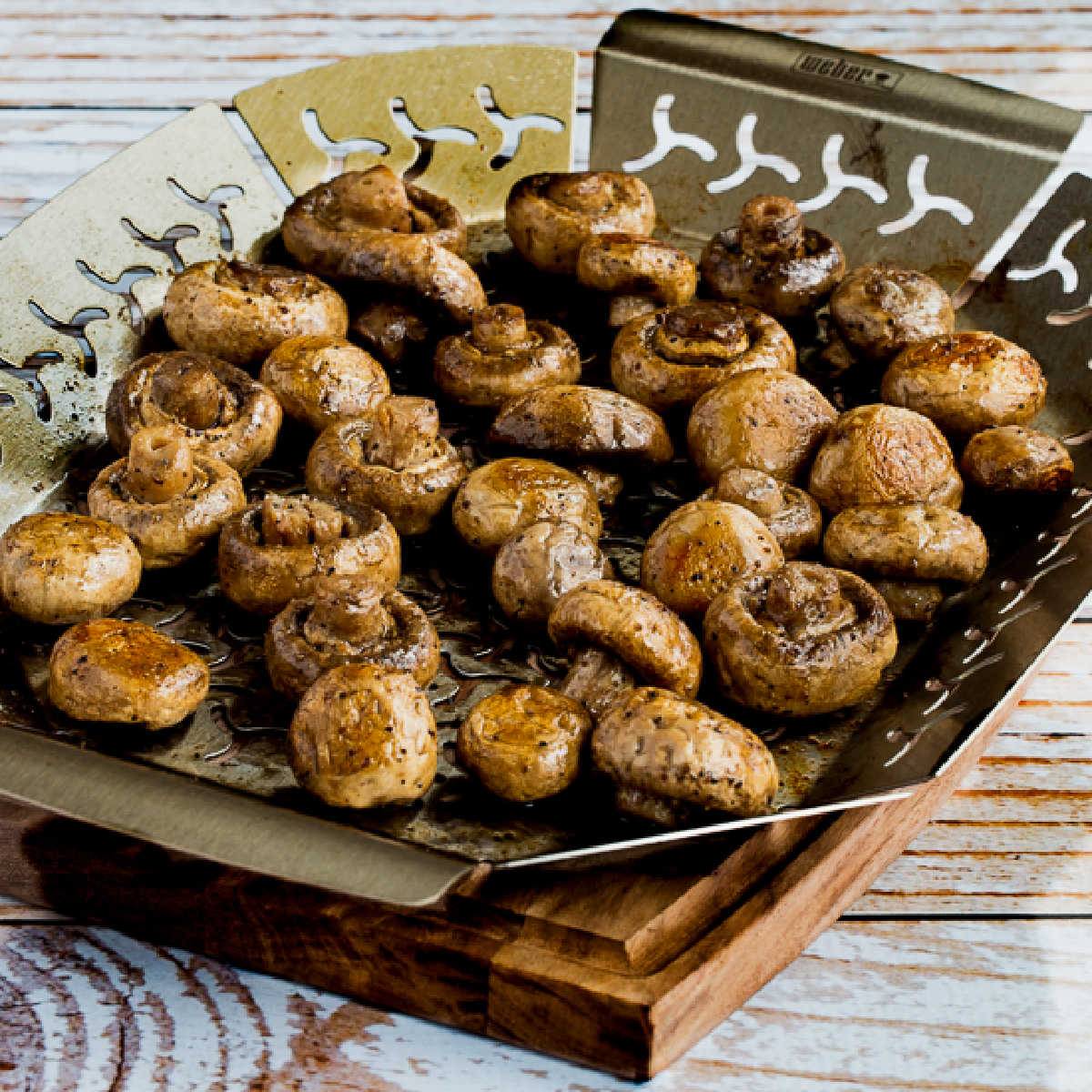 Square image of grilled mushrooms shown in grilling pan with holes.