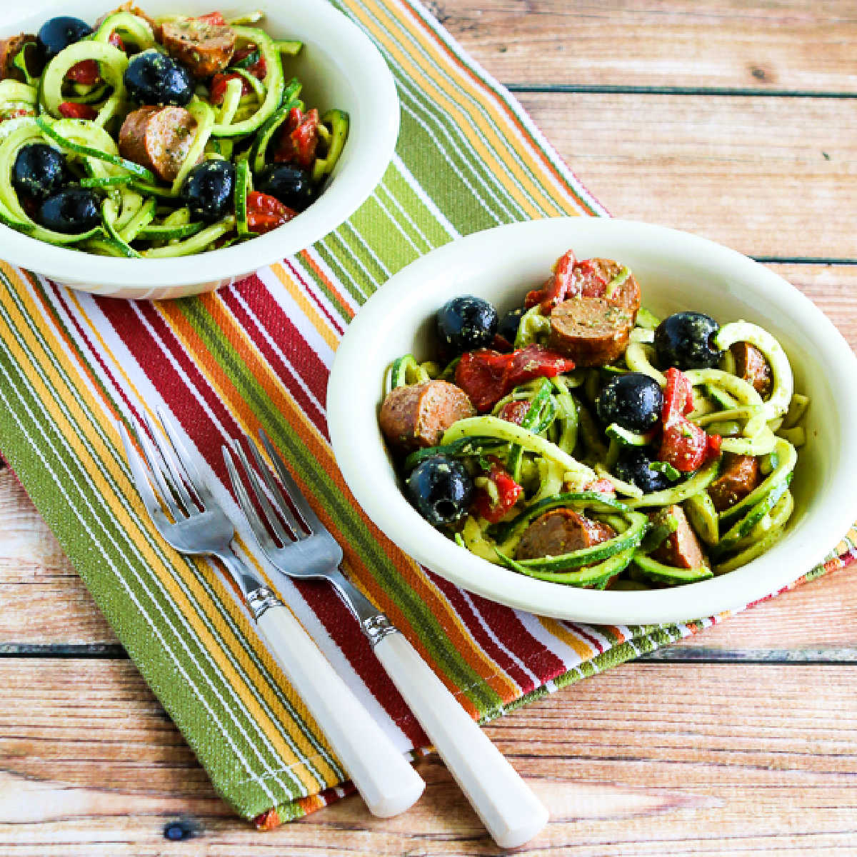 Zucchini Noodle Mock Pasta Salad shown in two bowls on striped napkin.