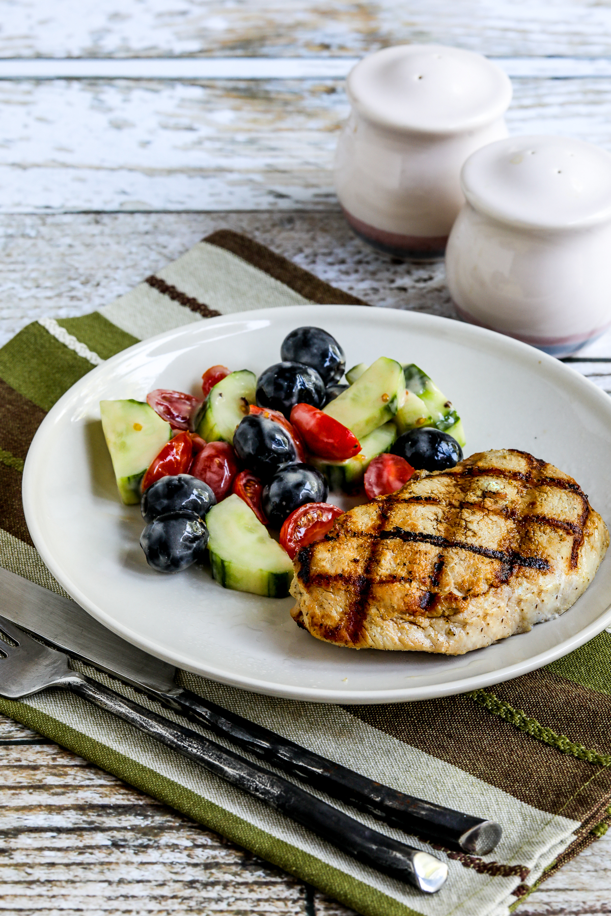 Grilled boneless pork chops are served on a plate with salad.
