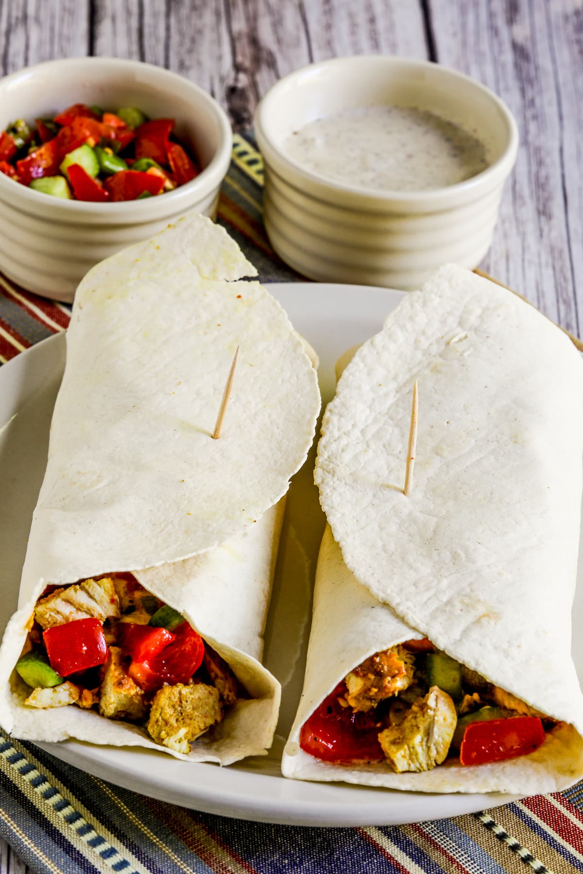 Chicken Shawarma Wrap with two wraps on serving plate with yogurt sauce and tomato-cucumber salsa
