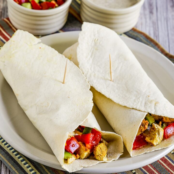 square image of Chicken Shawarma Wrap on plate with sauce and tomato-cucumber salsa