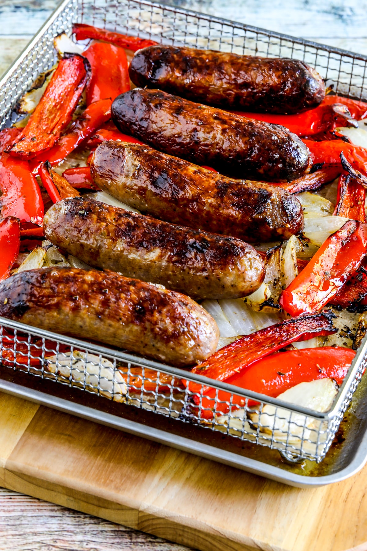 Air fryer sausages and peppers displayed in an air fryer basket