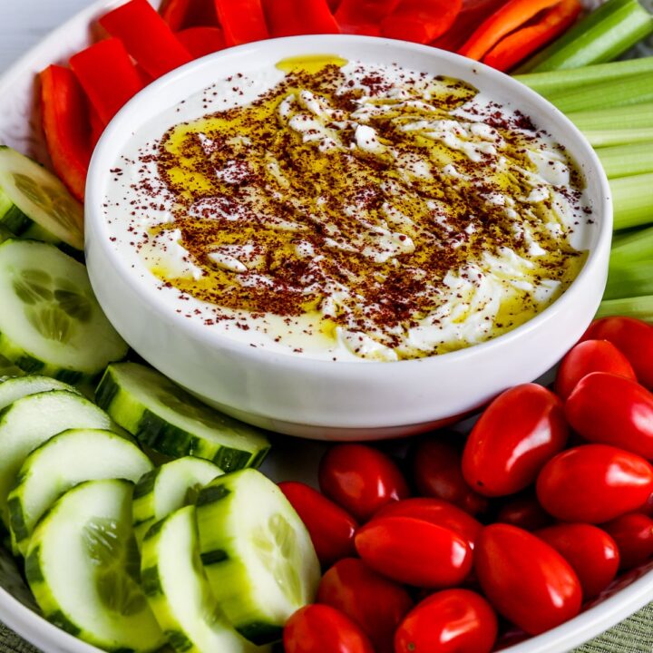 Whipped Feta Dip with Sumac shown on serving plate with tomatoes, cucumber, celery, and red pepper strips