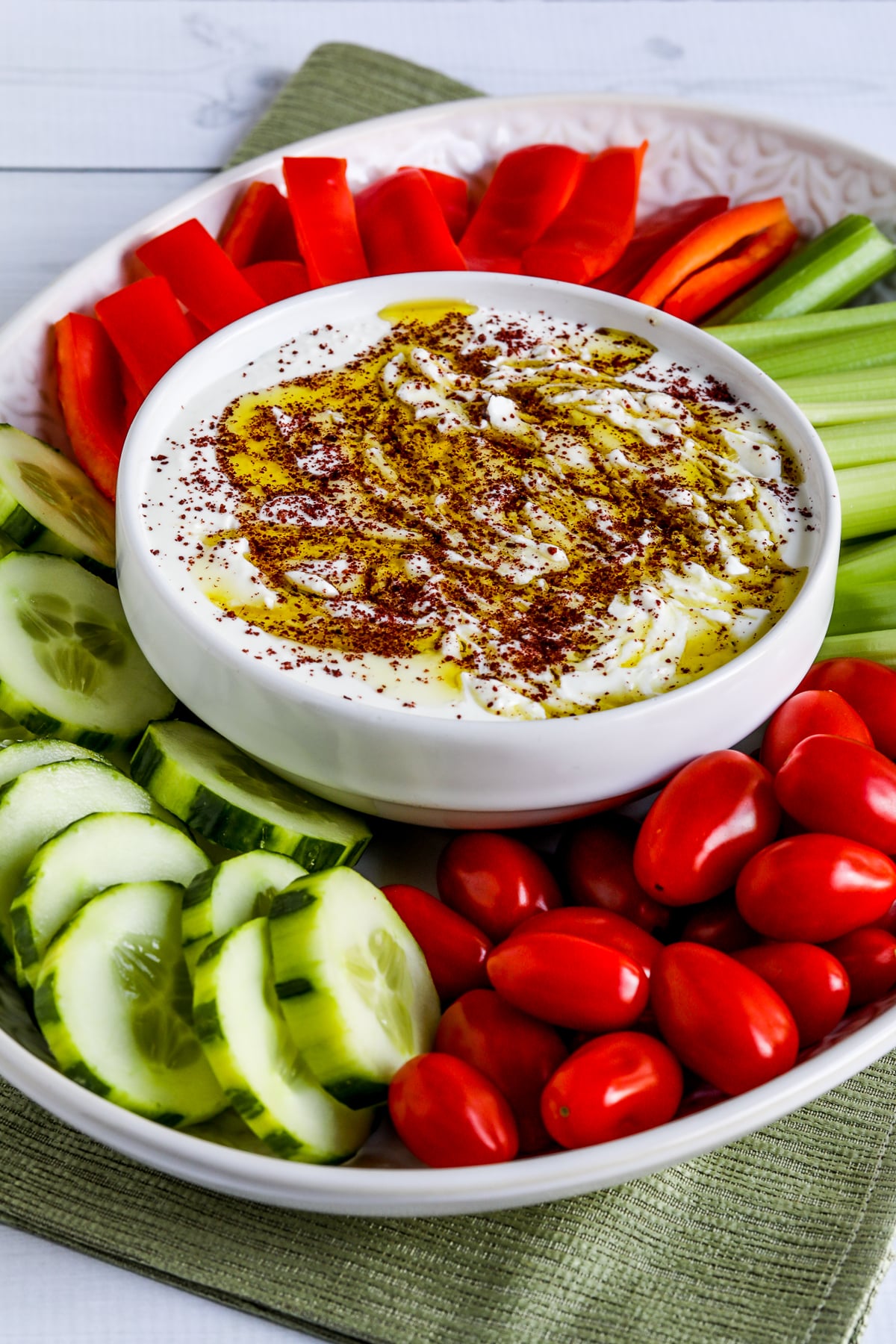 Whipped Feta Dip with Sumac shown on serving plate with tomatoes, cucumber, celery, and red pepper strips