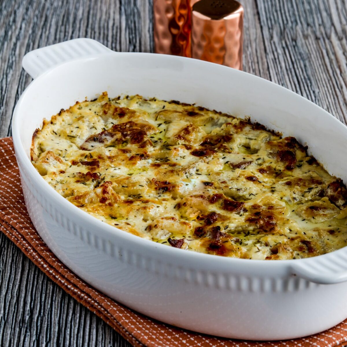 Turnip Gratin with Bacon shown in baking dish with salt-pepper in back.