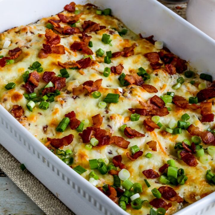Keto Crack Chicken Bake shown in baking dish with bacon and green onion sprinkled on