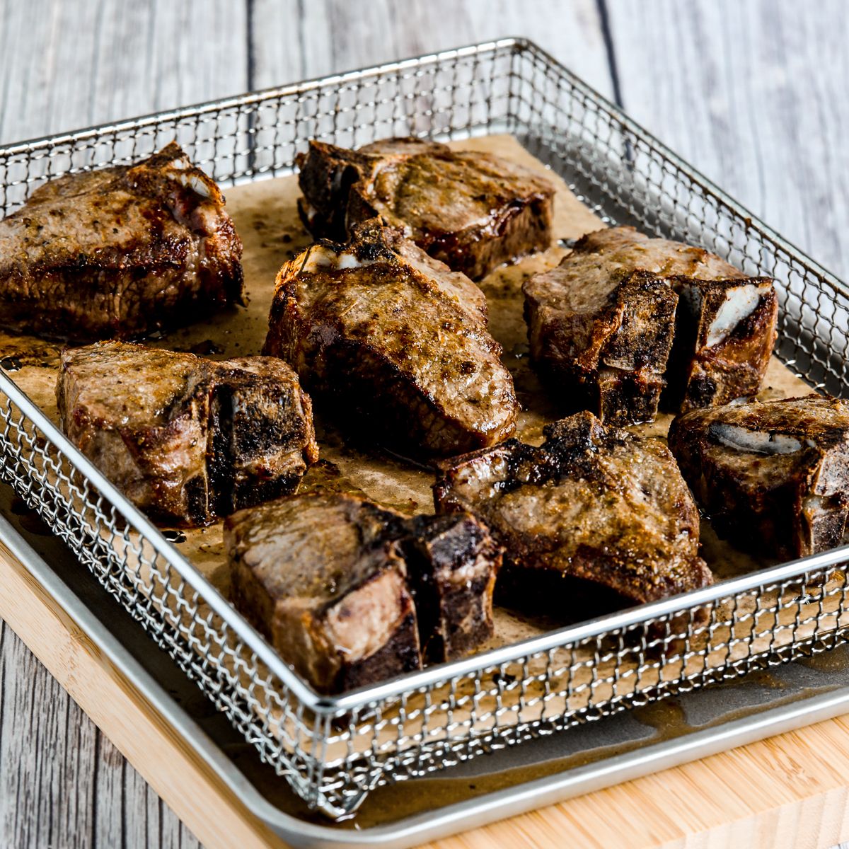 A square image of lamb chops in an air fryer basket.