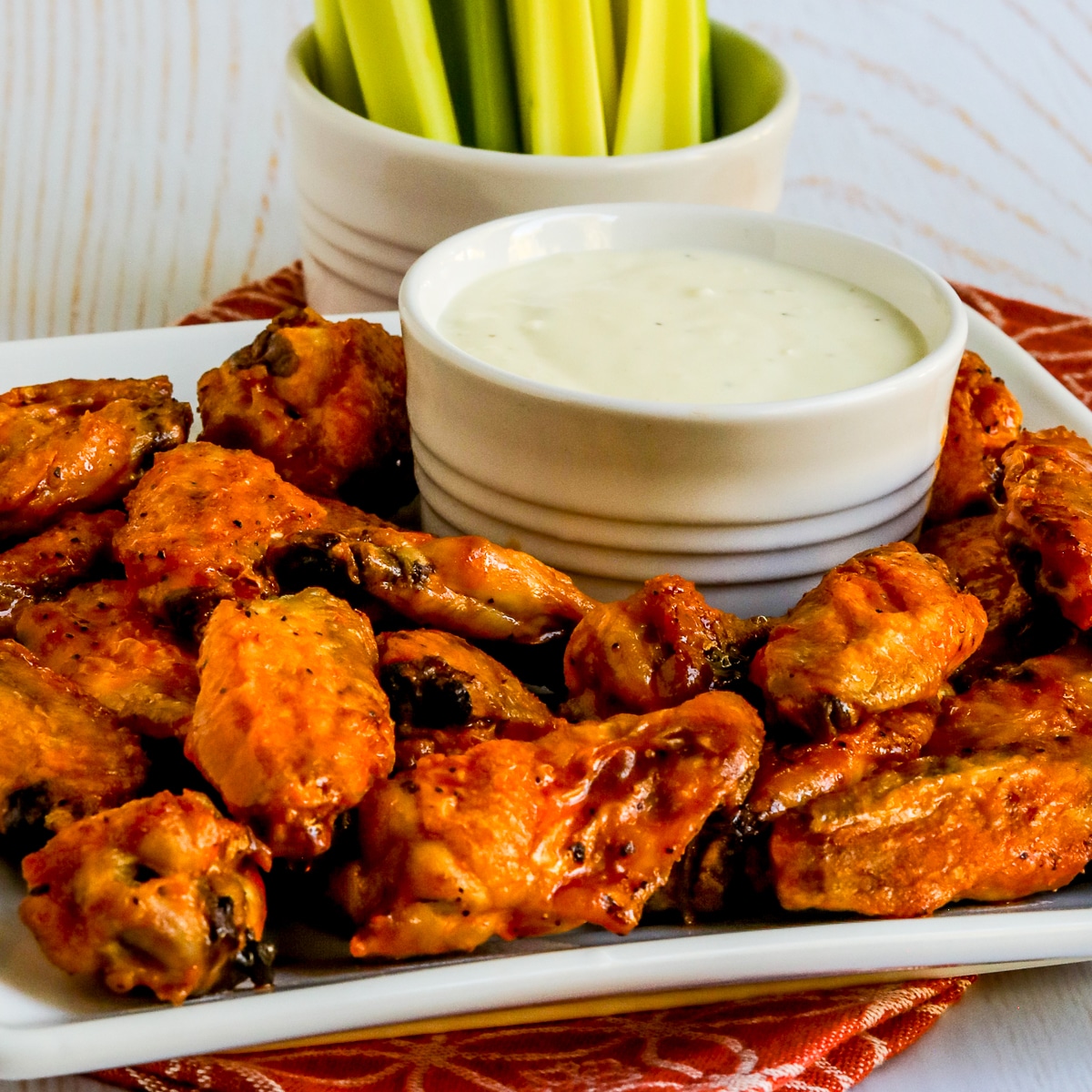 Square image of Air Fryer Buffalo Wings shown on serving platter with blue cheese dip and celery.