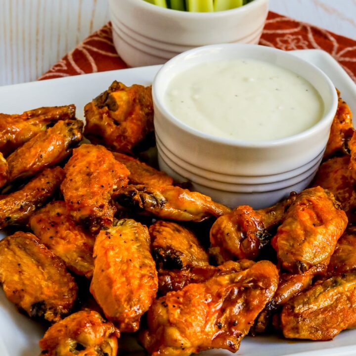 Air Fryer Buffalo Wings shown on tray with blue cheese dipping sauce and celery in back.
