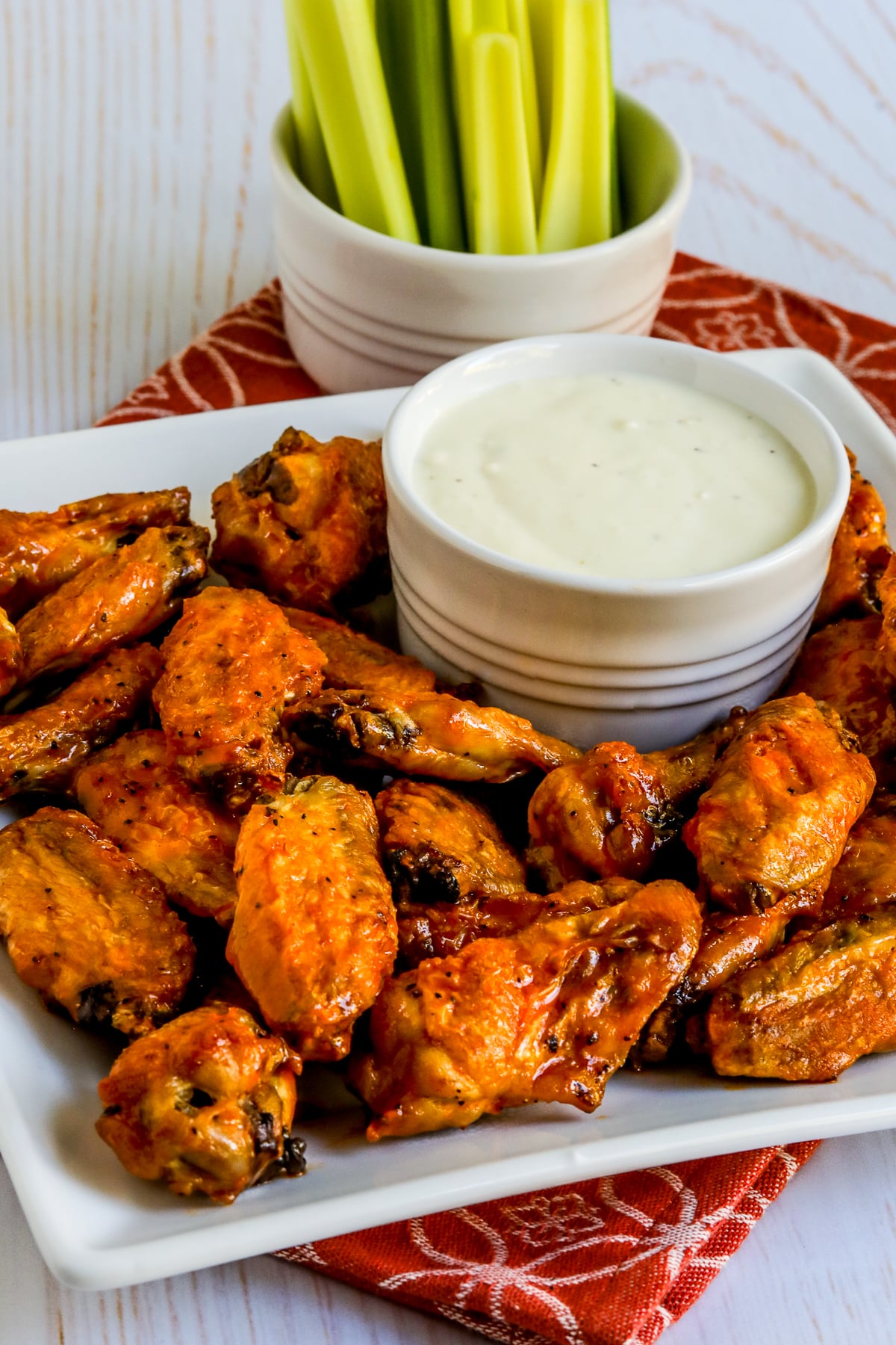 Air Fryer Buffalo Wings shown on tray with blue cheese dipping sauce and celery in back.